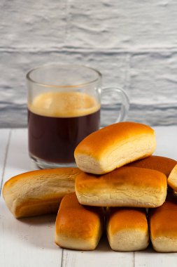 Beyaz ahşap bir masada birkaç mini çörek ve bir kupa kahve. Seçici odak.