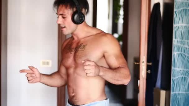 Handsome Muscular Young Man Using Headphones Alone Home Singing Jumping — стоковое видео