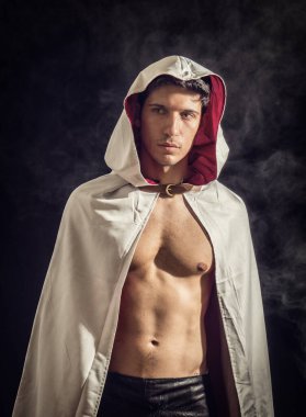 Eski moda pelerinli yakışıklı genç adam koyu dumanlı arka planda