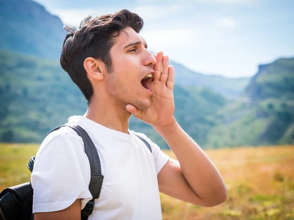 Young Travelling Male Backpack Standing Field Mountain Range Calling Out — Stock Photo, Image