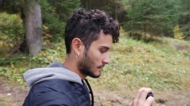 Güneşli ve huzurlu bir günde gölde yakışıklı bir genç adam manzaranın aksiyon kamerasıyla video kaydediyor.