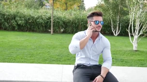 Trendy Pohledný Muž Elegantní Košili Pomocí Mobilu Sedí Kamenné Lavičce — Stock video