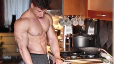 Gömleksiz erkek vücut geliştirici evde mutfakta yemek pişiriyor, yemek hazırlıyor.