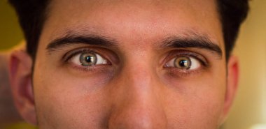 Close-up of attractive young mans green eyes, looking at camera