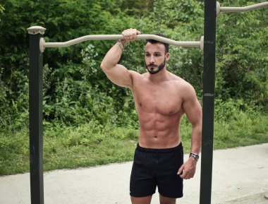 egzersiz ve şehir parkı açık spor salonunda egzersiz çekici üstsüz genç adam