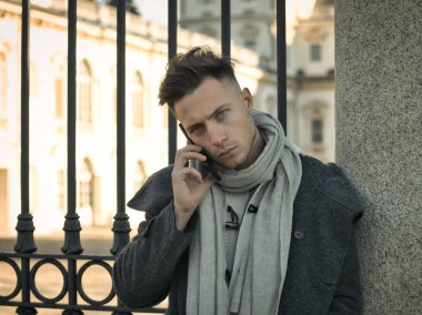 Trendy yakışıklı giyen beyazlı duran ve cep telefonuyla, gün atış şehir ortamda açık söz