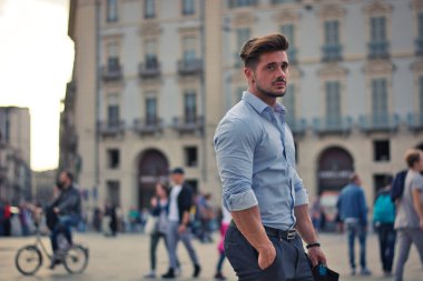 One handsome elegant man in urban setting in European city, standing, wearing shirt. Side view