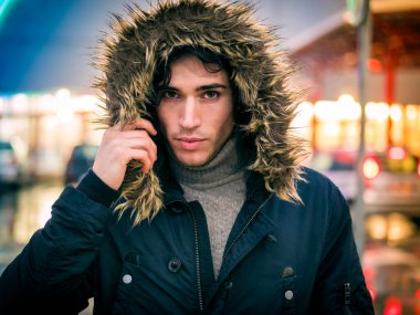 Full length of young man in coat walking under rain along the city street