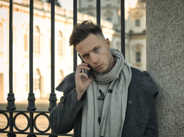 stock image Handsome trendy man wearing white shirt standing and talking on cell phone, outdoor in city setting in day shot