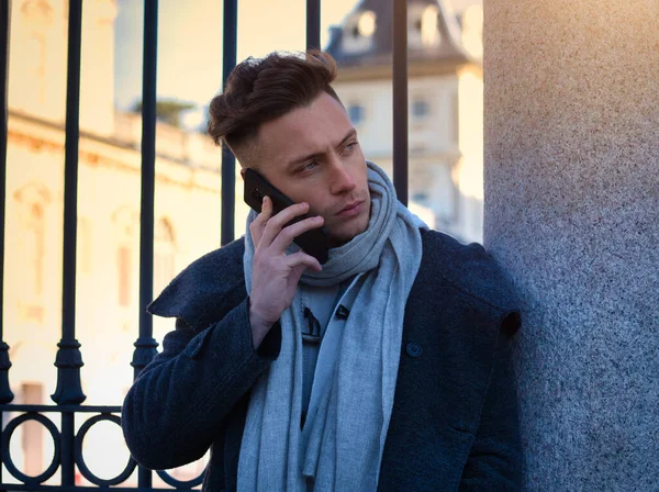 Trendy yakışıklı giyen beyazlı duran ve cep telefonuyla, gün atış şehir ortamda açık söz