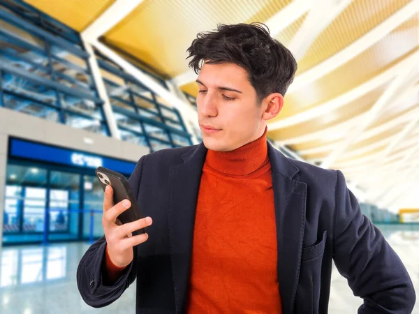 Bir tarafa, ciddi görünümlü yakışıklı genç işadamı cep telefonuyla konuşurken ofisinde