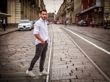 Avrupa 'nın caddesinde yürüyen genç ve çekici bir adam, kameraya bakıyor.