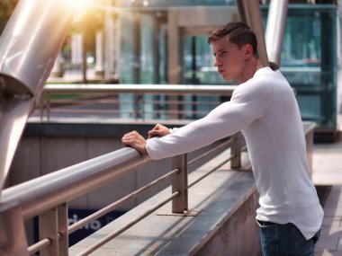 Şehirde beyaz gömlek ve kot pantolon giyen kaslı genç adam.