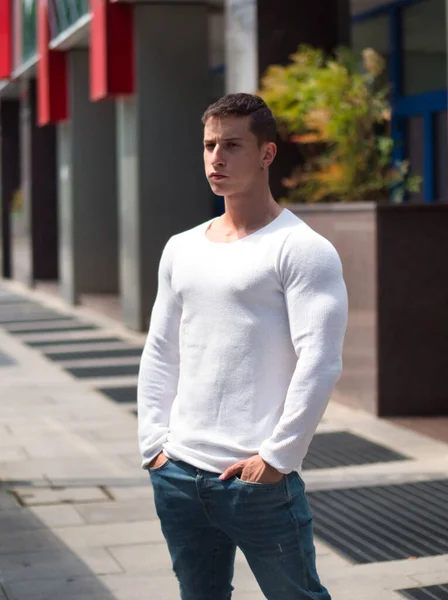 都市背景下身穿白衬衫和牛仔裤的肌肉发达的年轻人 — 图库照片