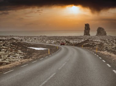 Modern araba İzlanda gezisi sırasında asfalt kırsal yolda muhteşem karlı dağlara doğru gidiyor.