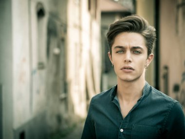 Avrupa 'nın kentsel ortamında yakışıklı, zarif bir genç adam güneşli bir günde kameraya bakıyor.