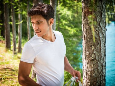 Güneşli, huzurlu bir günde gölde yakışıklı genç bir adam, bir tarafa bakıyor.