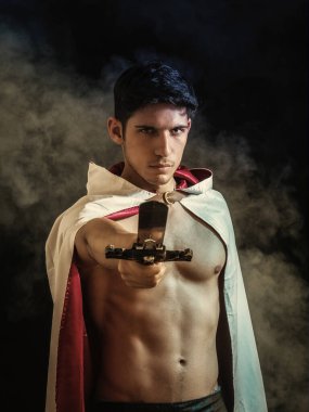 Eskimiş pelerinli çıplak gövdeli, ciddi, güçlü, genç, İspanyol bir erkek. Kılıcını uzatıp, kameraya meydan okuyor.