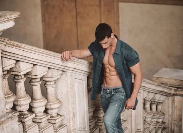 裸露躯干上开衬衫 爬上大理石楼梯 靠铁路在古典建筑内的迷人年轻肌肉男的画像 — 图库照片
