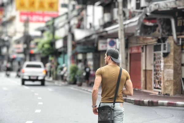 タイのバンコクで忙しい日当たりの良い通りを歩く若いフィット感の男のバックビュー — ストック写真