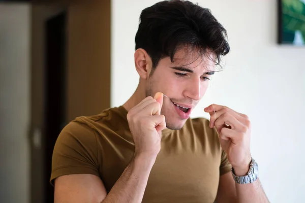 自宅での毎日の衛生的な手順中に歯科フロスで若い男性のクリーニング歯 — ストック写真