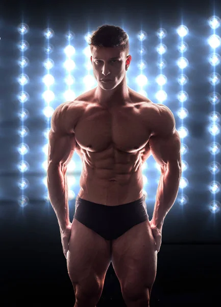 全裸肌肉的男性健美运动员 穿着黑色衣服 身后有戏剧性的舞台照明 — 图库照片