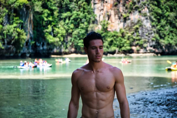在泰国普吉岛的一个海滩上 一名年轻英俊的 肌肉发达的男子穿着短裤赤身裸体地站在海滩上 向旁边看去 他的半身像被打了一针 — 图库照片