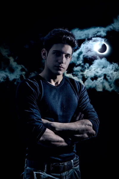 月と夜の空の下でハンサムな若い男 劇的なショットでカメラを見て — ストック写真