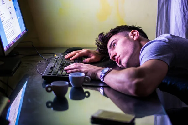 夜のオンライン作業中に画面を見てキーボード上の手でテーブルの上に横たわる若い疲れ男の高い角度 — ストック写真