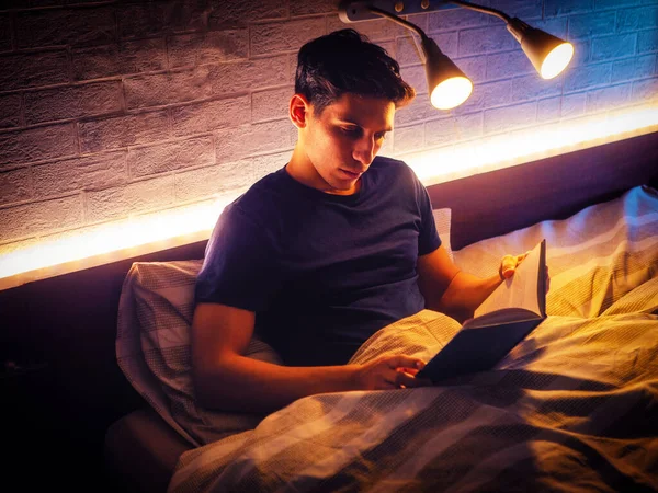 Νεαρός Ελκυστικός Άντρας Ξαπλωμένος Στο Κρεβάτι Και Διαβάζοντας Ένα Βιβλίο — Φωτογραφία Αρχείου