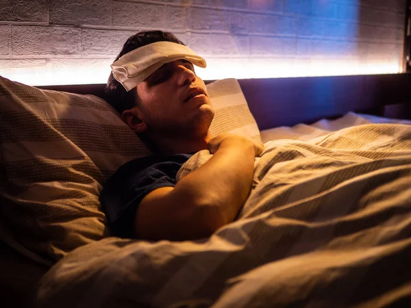 目を閉じて額に湿った布で インフルエンザや発熱とベッドの中で若いハンサムな病気や不健康な男 — ストック写真