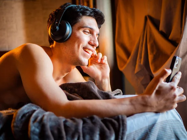 매력적 헤드폰을 사용하여 침대에 음악을 즐거운 시간을 보내고 — 스톡 사진