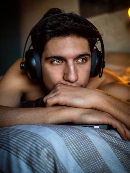 Attraktiv Ung Man Med Hörlurar Liggande Ensam Sängen Lyssna Musik — Stockfoto