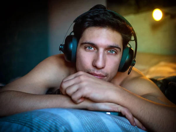 Привлекательный Молодой Человек Пользующийся Наушниками Лежащими Одиночестве Кровати Слушающий Музыку — стоковое фото