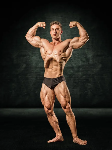 Knappe Shirtloze Gespierde Man Doet Klassieke Bodybuilding Pose Donkere Achtergrond — Stockfoto