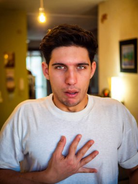 Acı çeken adam kameraya bakıp elini göğsüne koyuyor ve bulanık daireye karşı kalp ağrısı hissediyor.