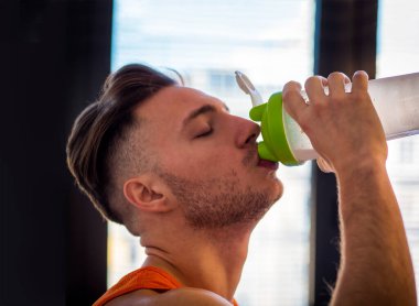 Genç adam sağlıklı güler yüzlü içki içme blender veya shaker bir protein shake
