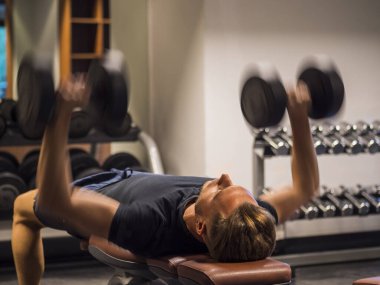 Kas yığını genç adam, halterleri kaldırıyor spor salonunda göğüs kası çalıştırıyor.