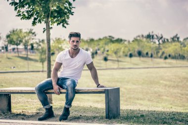 Şehir parkında güzel bir yaz gününde çekici kaslı bir adam.