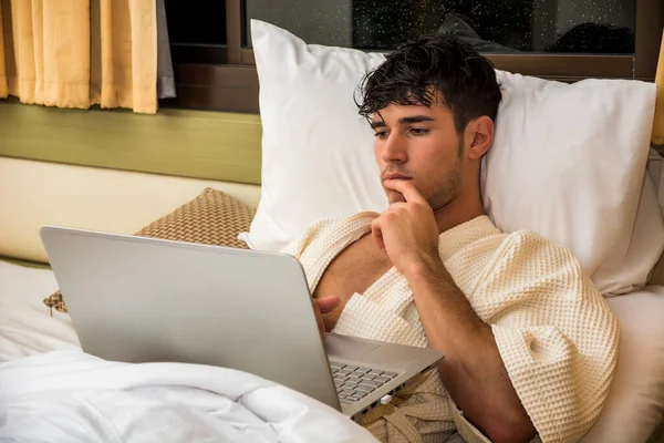 Attractive Young Man Serious Expression Reclining Comfortably Laptop Bed Working — Stock Photo, Image