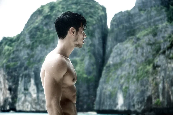 タイのプーケット島のビーチに立っているハンサムな若い男の半分の体のショットは 筋肉フィットボディを示す ボクサーショーツを身に着けている — ストック写真