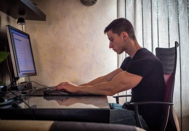 Siyah Saçlı Genç Çekici Adam 'ın Belden Kalkışı Profili, Bilgisayar Masasında Oturmak, Kağıt Ödevi Üzerinde Çalışmak, Ya da Yurt Odası' ndaki İş Kuruluşu Üzerine Çalışmak