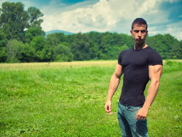 緑の公園のハンサムな筋肉のハンクのヤングマン屋外 木と草原 ブラックTシャツを着ています — ストック写真