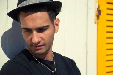 Duvara yaslanmış, yana bakan yakışıklı bir adamın portresi.