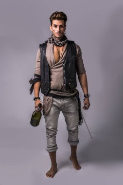 Korsan moda kıyafet gri arka plan üzerinde iyi görünümlü genç adam. Studio yakalanan.