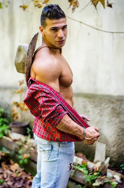 Красивый Мускулистый Молодой Человек Снимает Рубашку Носит Джинсы Соломенную Шляпу — стоковое фото
