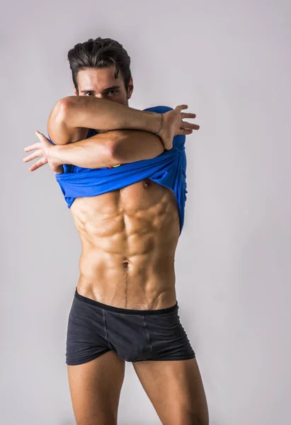 Schöner Muskulöser Junger Mann Der Sein Shirt Auszieht Auf Grauem — Stockfoto