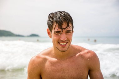 Tayland, Phuket Adası 'nda bir plajda duran yakışıklı genç adam. Üstsüz, boxer şort giyiyor. Kaslı, fit bir vücut gösteriyor.