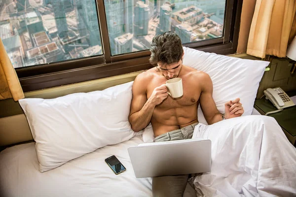 赤身裸体 肌肉发达的年轻人 手拿杯子或杯子 手拿着咖啡或茶 看着笔记本电脑的电脑屏幕 — 图库照片