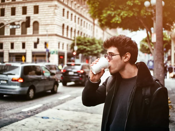 迷人的年轻人在现代城市中心喝着纸杯咖啡 穿着皮夹克 — 图库照片